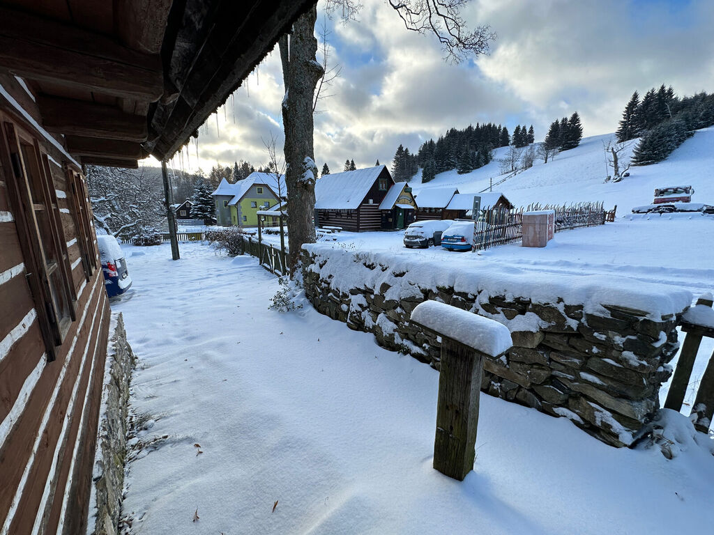 Pohled od Roubenky 42 přes zasněženou kamennou zídku na sousední chalupy